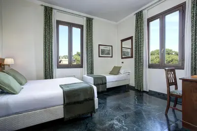 a bedroom with two beds and a desk and windows at Grand Hotel Gianicolo in Rome