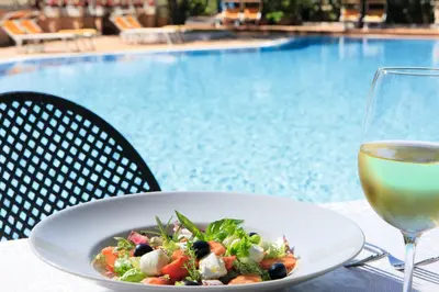 a plate of salad and a glass of wine next to a pool at Grand Hotel Gianicolo in Rome