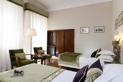 a hotel room with two beds and a chair at Bettoja Hotel Atlantico in Rome