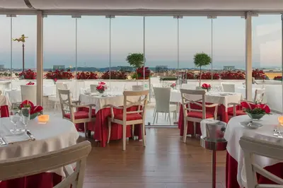 a restaurant with white tables and chairs and windows at Bettoja Hotel Mediterraneo in Rome