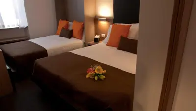 two beds in a hotel room with flowers on them at Hotel Concordia in Rome