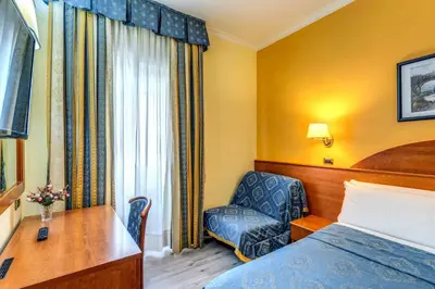 a hotel room with a bed and a chair and a desk at Baltik Guesthouse in Rome