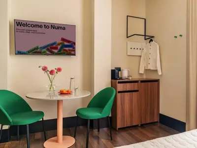 a room with a table and two green chairs at Numa Rome Barberini in Rome