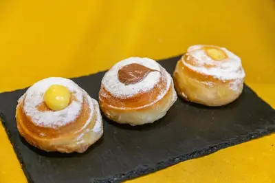 three donuts with powdered sugar on a black tray at Best Western Hotel Piccadilly in Rome