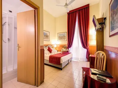 a hotel room with a bed and a table and a door at Hotel Giotto Flavia in Rome