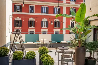 a courtyard with tables and plants in front of a building at The Spring House Hotel Rome Vatican, Tapestry Collection Hilton in Rome