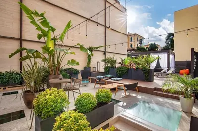 a rooftop patio with plants and a swimming pool at The Spring House Hotel Rome Vatican, Tapestry Collection Hilton in Rome