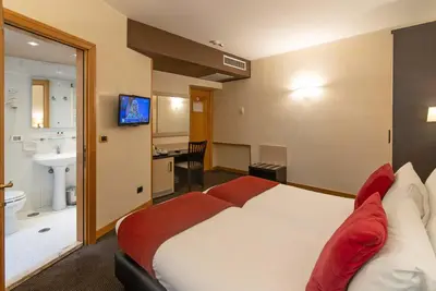 a hotel room with a large bed and a bathroom at Hotel Tritone in Rome