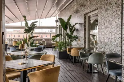 a restaurant with tables and chairs and plants at La Griffe Hotel Roma in Rome