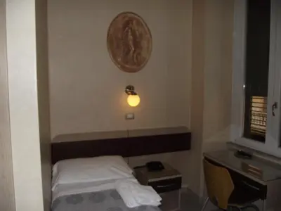 a small room with a bed and a light on the wall at Hotel Elide in Rome