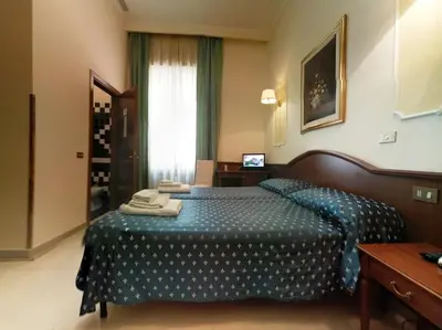 a bedroom with a bed with a blue comforter at Cambridge Hotel in Rome