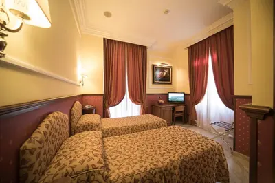 a hotel room with two beds and red curtains at Hotel Donatello in Rome