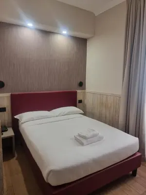 a bedroom with a white bed with a red headboard at Hotel Pyramid in Rome