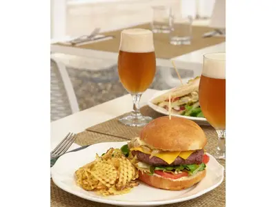 a plate with a hamburger and fries and two glasses of beer at Golden Tulip Rome Piram in Rome