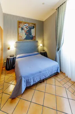 a bedroom with a bed with a blue bedspread at Hotel Lirico in Rome