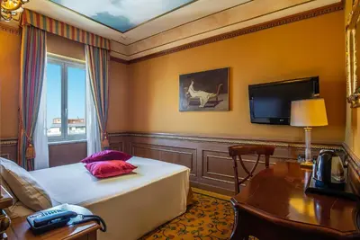 a bedroom with a bed and a desk and a tv at River Palace Hotel in Rome