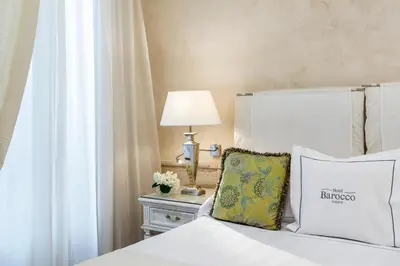 a bedroom with a bed and a lamp on a table at Hotel Barocco in Rome