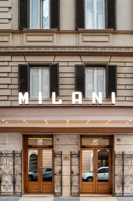 two people standing at a reception desk in a lobby at Hotel Milani in Rome