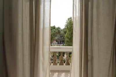 a window with curtains with a view of a balcony at Lucky Stars rooms in Rome