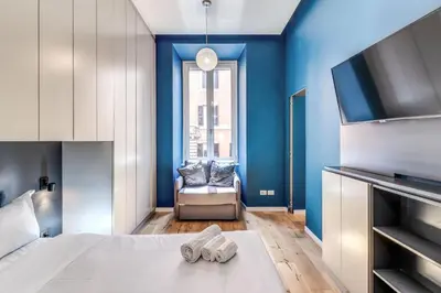 a bedroom with blue walls and a bed and a chair at Domus in Piazza del Popolo in Rome