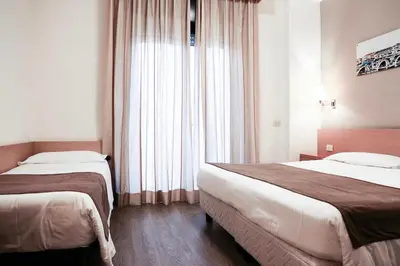 a hotel room with two beds and a window at Hotel Sisto V in Rome