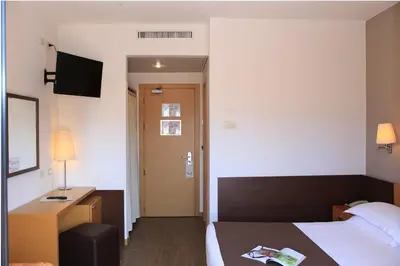 a hotel room with a bed and a desk and a door at Hotel Sisto V in Rome