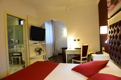 a hotel room with a bed and a desk and a television at Trilussa Palace Hotel Congress & Spa in Rome
