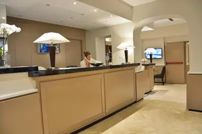 a man sitting at a reception desk in a hotel lobby at LH Hotel Lloyd Roma in Rome