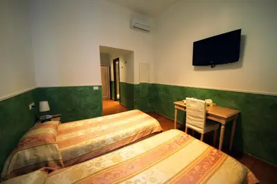 a room with two beds and a desk and a television at Residenza Ki in Rome