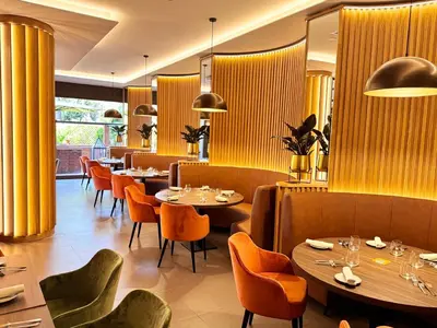 a restaurant with tables and chairs and yellow curtains at Crowne Plaza Rome St. Peter's by IHG in Rome