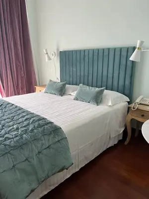 a bedroom with a large bed with a blue headboard at Hotel Fenix in Rome