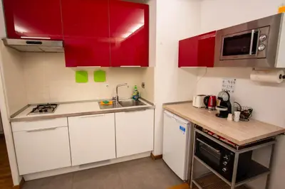 a small kitchen with red cabinets and a sink at Saint Peter Apartment in Rome