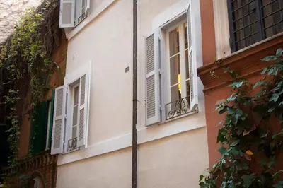 a building with white shuttered windows on a street at Casa Fabbrini Boutique B&B in Rome