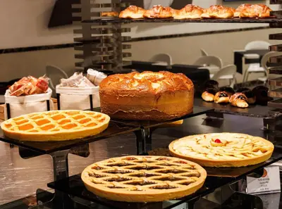 a bunch of cakes and waffles on display in a bakery at Best Western Premier Hotel Royal Santina in Rome
