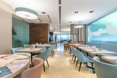 a restaurant with tables and chairs and a large window at Hilton Garden Inn Rome Claridge in Rome