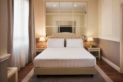 a bedroom with a bed with two lamps and a mirror at Radisson Blu GHR Rome in Rome