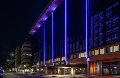 a building with purple lights on the side of it at NYX Hotel Rome by Leonardo Hotels in Rome