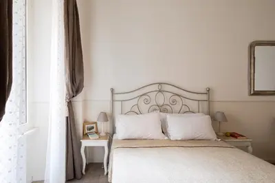 a bedroom with a bed with white sheets and a window at Dante's in Vaticano in Rome
