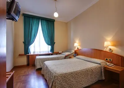 a hotel room with two beds and a window at Hotel Corot in Rome