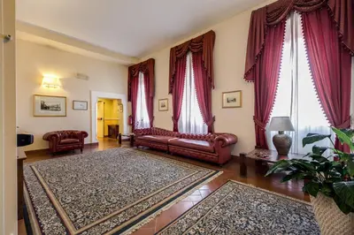 a living room with red leather couches and curtains at Relais Hotel Antico Palazzo Rospigliosi in Rome
