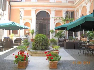 an outdoor patio with flowers and tables and umbrellas at Relais Hotel Antico Palazzo Rospigliosi in Rome