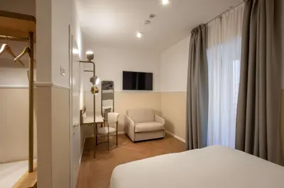 a hotel room with a bed and a chair at Cosmopolita Rome Colosseum, Tapestry Collection by Hilton in Rome
