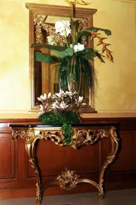 a vase with flowers on a table in front of a mirror at Hotel Champagne Palace in Rome