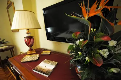 a table with a lamp and a vase of flowers on it at Residenza Paolo VI in Rome