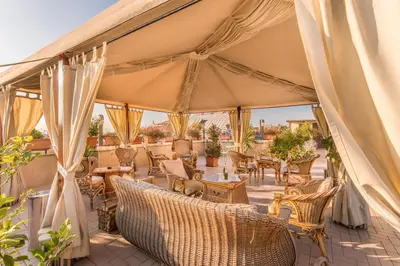 a covered patio with wicker chairs and tables at Hotel Impero in Rome