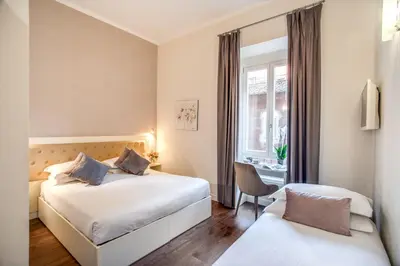 a hotel room with two beds and a window at Hotel San Silvestro in Rome