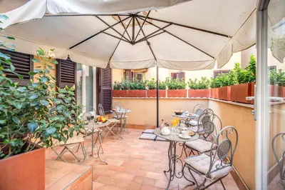 a patio with tables and chairs and an umbrella at Hotel San Silvestro in Rome