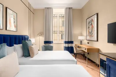 a hotel room with two beds and a desk at Room Mate Collection Mia, Rome Colosseum in Rome