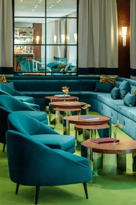 a waiting room with blue couches and tables and tables at Room Mate Collection Mia, Rome Colosseum in Rome