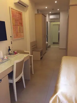 a hotel room with a bed and a desk and a hallway at Augustana House and Suites in Rome